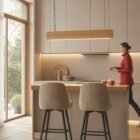Singular Lighting - NINA Pendant P120-10B A natural oak pendant light (the 'Nina' lamp) illuminating a light wood kitchen counter with two upholstered bar stools.