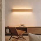 nina-wall-oak-linear-up-down-lighting-living-room Nina Wall linear wooden up-and-down lamp by Singular Lighting, in a minimal living room above an oak console with a leather chair. Warm ambient light, natural oak finish.