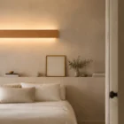 Bedroom view of the wooden Nina Wall linear lamp by Singular Lighting, mounted above a minimalist bed. Soft, natural lighting and simple decor.